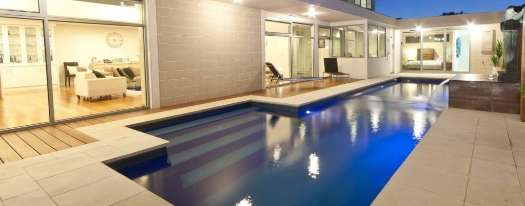 ibreglass lap pool with entry steps and a water wall water feature